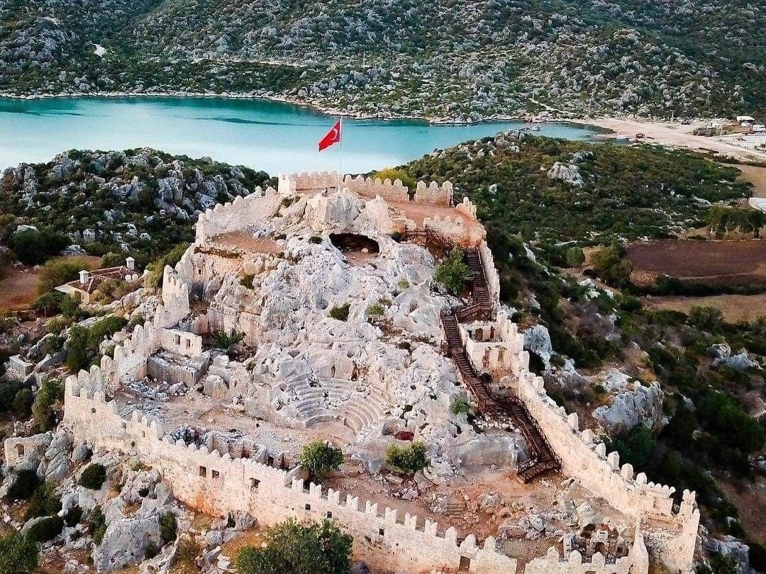 Simena Castle from the air — the small ancient theatre inside the walls, with the bay and mountains behind